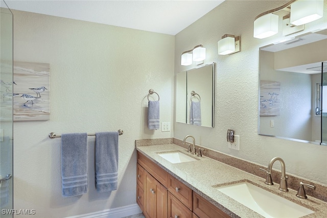 bathroom with double vanity, a sink, and a textured wall