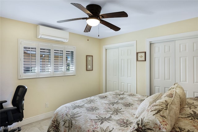 bedroom featuring a ceiling fan, baseboards, multiple closets, an AC wall unit, and tile patterned floors