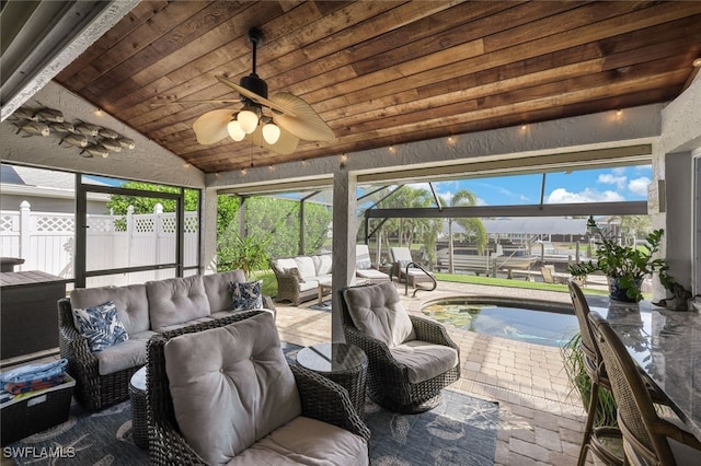 sunroom with lofted ceiling, a wealth of natural light, wood ceiling, and a ceiling fan