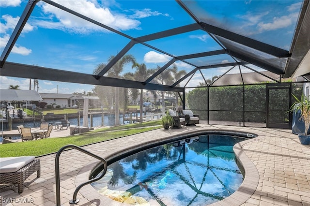 outdoor pool with glass enclosure, a patio area, a water view, and a lawn