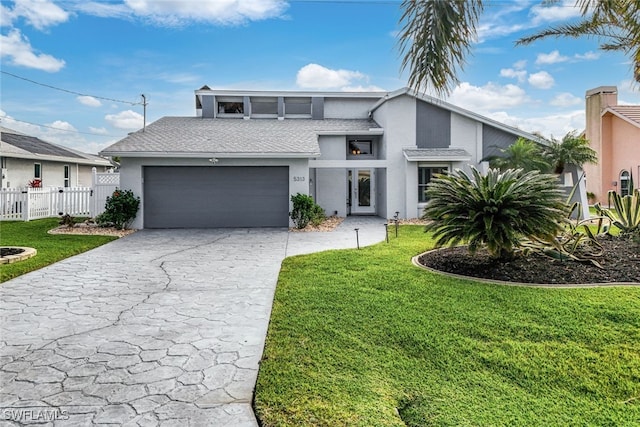 view of front of house with a garage, fence, a front lawn, and stucco siding