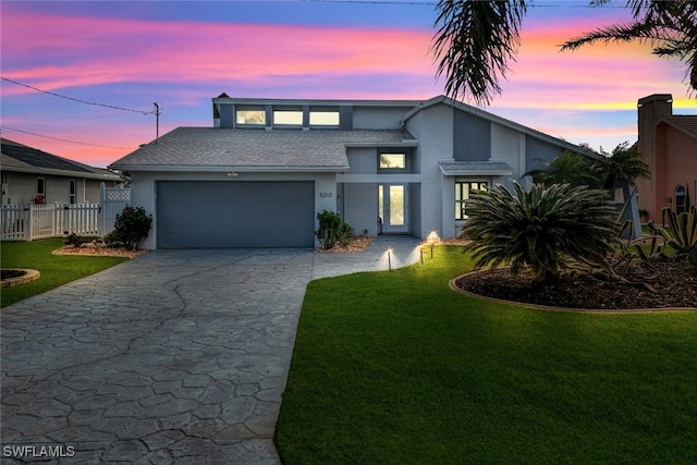 view of front facade with concrete driveway, fence, an attached garage, and a lawn