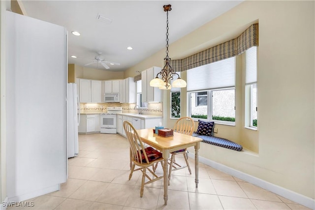 tiled dining space with ceiling fan with notable chandelier and sink