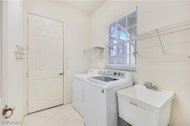 clothes washing area with sink, washer and clothes dryer, and light tile patterned floors