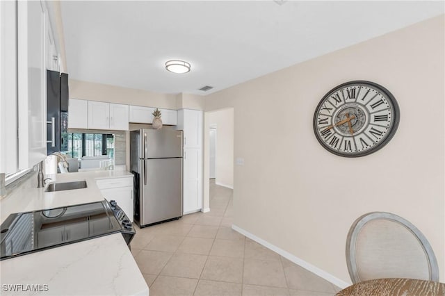 833 Reef Point Cir, Naples, FL 34108 - kitchen with white cabinets, sink, stainless steel refrigerator, light tile patterned flooring, and light stone counters