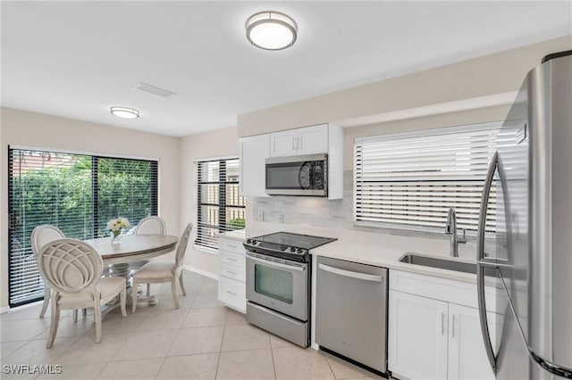 833 Reef Point Cir, Naples, FL 34108 - kitchen featuring appliances with stainless steel finishes, white cabinetry, light tile patterned floors, decorative backsplash, and sink
