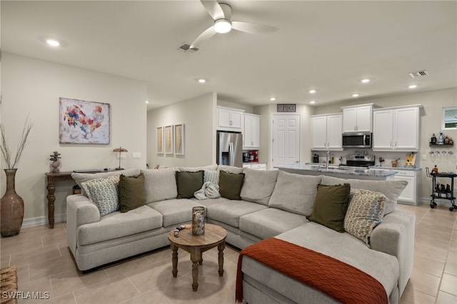 tiled living room featuring ceiling fan and sink