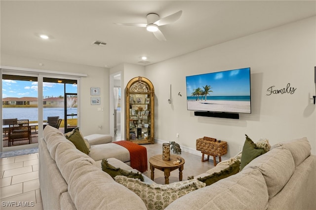 tiled living room with a water view and ceiling fan