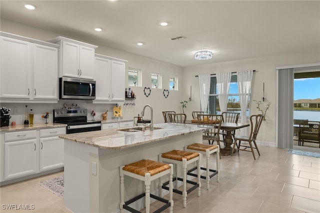 kitchen featuring an island with sink, appliances with stainless steel finishes, sink, and white cabinets