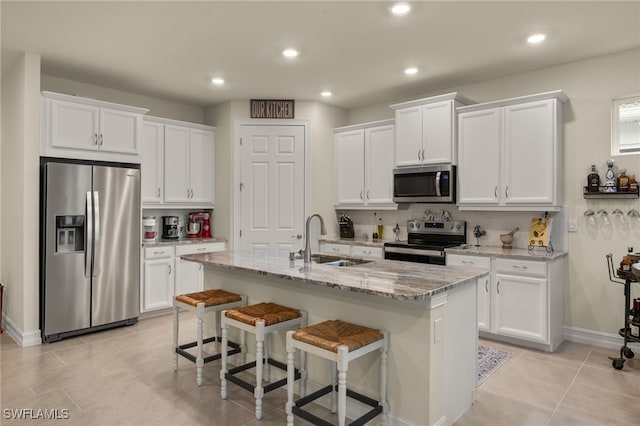 kitchen with a kitchen island with sink, sink, white cabinets, and appliances with stainless steel finishes