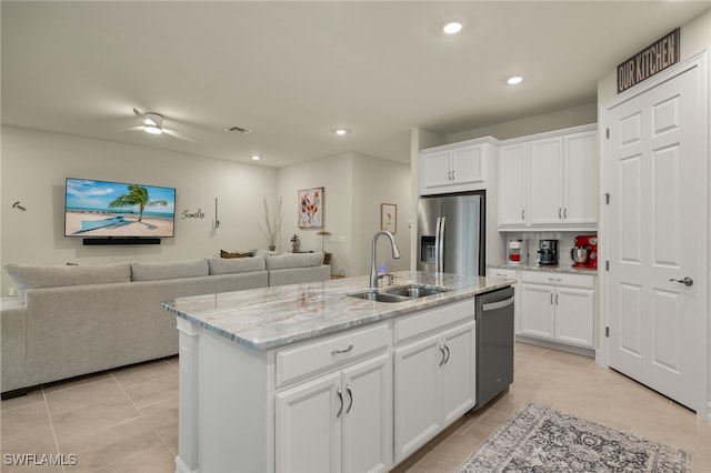 kitchen featuring sink, white cabinetry, light tile patterned floors, appliances with stainless steel finishes, and a kitchen island with sink