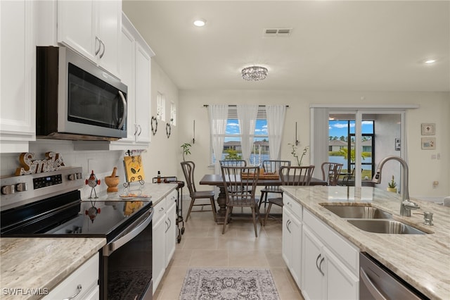 kitchen with stainless steel appliances, sink, white cabinets, and light stone counters