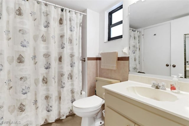 full bathroom featuring shower / tub combo with curtain, tile walls, vanity, tile patterned floors, and toilet