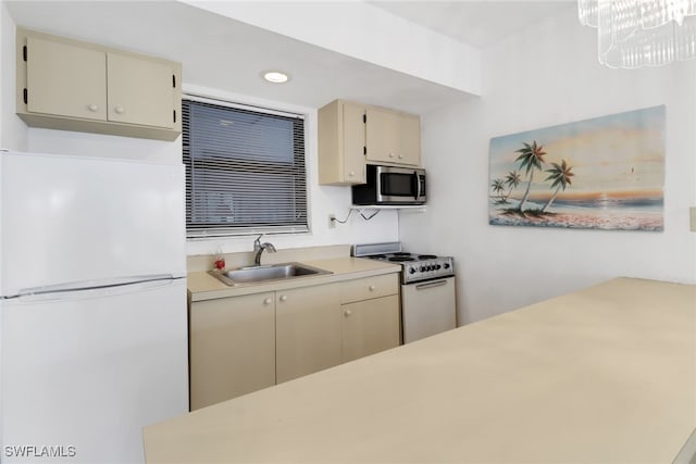 kitchen featuring hanging light fixtures, sink, white appliances, and cream cabinetry