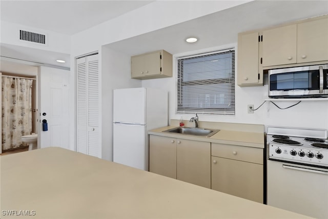 kitchen with sink, white appliances, and cream cabinetry