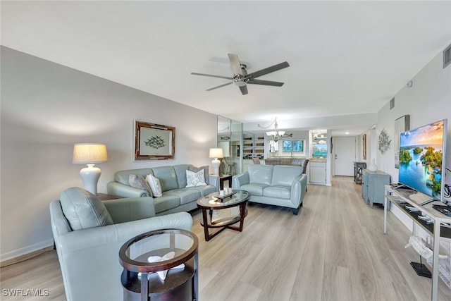 living room with ceiling fan with notable chandelier and light hardwood / wood-style floors