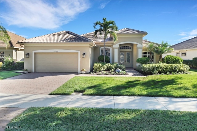 mediterranean / spanish house featuring a front lawn, french doors, and a garage