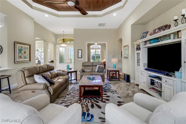 living room with ceiling fan, wood ceiling, and a tray ceiling