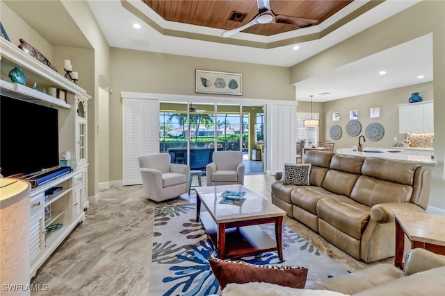 living room featuring ceiling fan, a raised ceiling, and wood ceiling