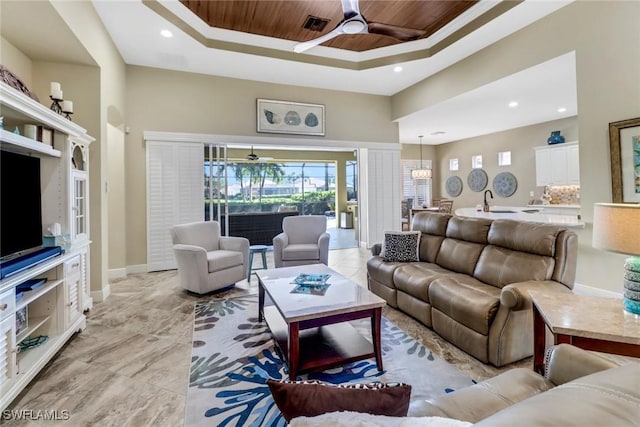 living room featuring ceiling fan, a tray ceiling, and wood ceiling