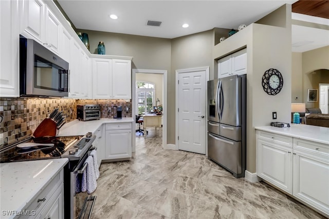 kitchen with stainless steel appliances, decorative backsplash, white cabinets, and light stone counters