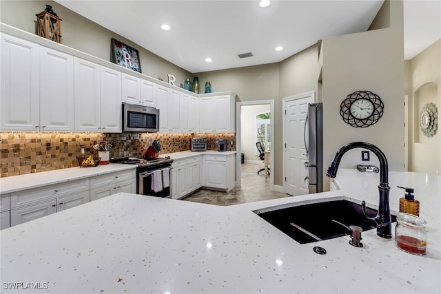 kitchen with white cabinets, backsplash, appliances with stainless steel finishes, and sink