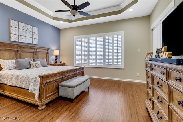 bedroom with ceiling fan, crown molding, a raised ceiling, and hardwood / wood-style floors