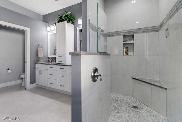 bathroom featuring toilet, a tile shower, and vanity