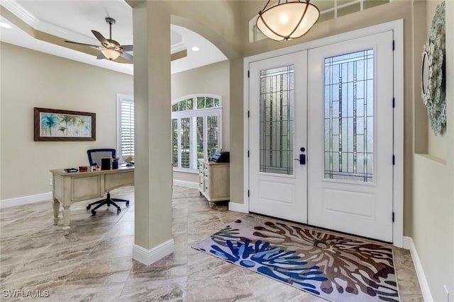 entryway with a raised ceiling, french doors, ornamental molding, and ceiling fan