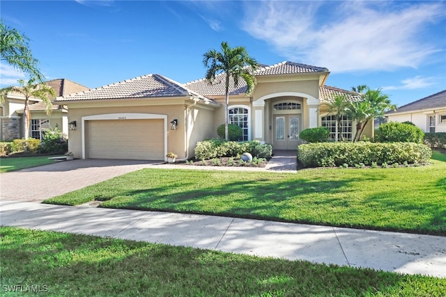 mediterranean / spanish-style house with a front yard, a garage, and french doors