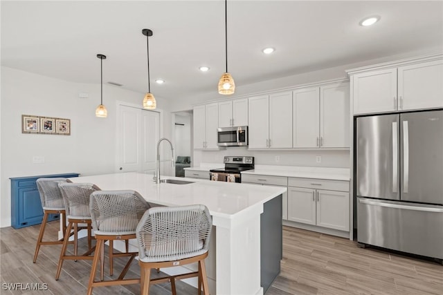 kitchen featuring white cabinetry, appliances with stainless steel finishes, sink, and a center island with sink