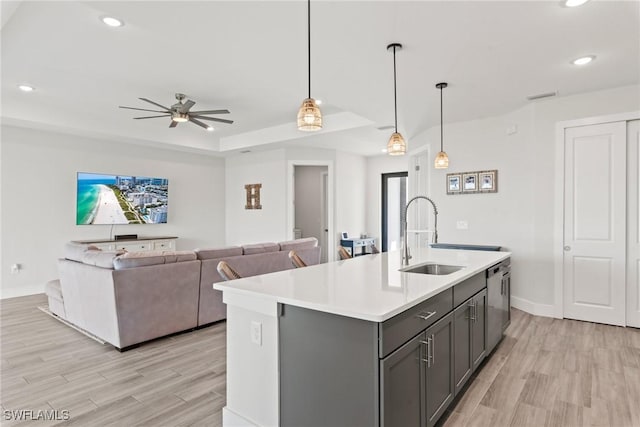 kitchen with sink, hanging light fixtures, stainless steel dishwasher, and an island with sink