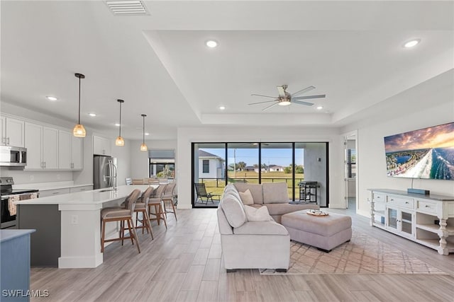 living room with a raised ceiling and ceiling fan