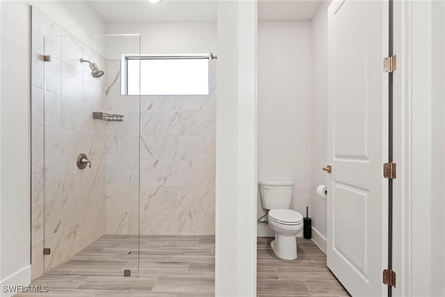 bathroom featuring a tile shower and toilet