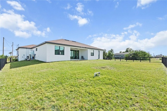 rear view of house with ceiling fan and a lawn