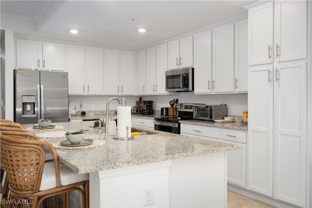 kitchen featuring sink, white cabinetry, an island with sink, stainless steel appliances, and light stone counters