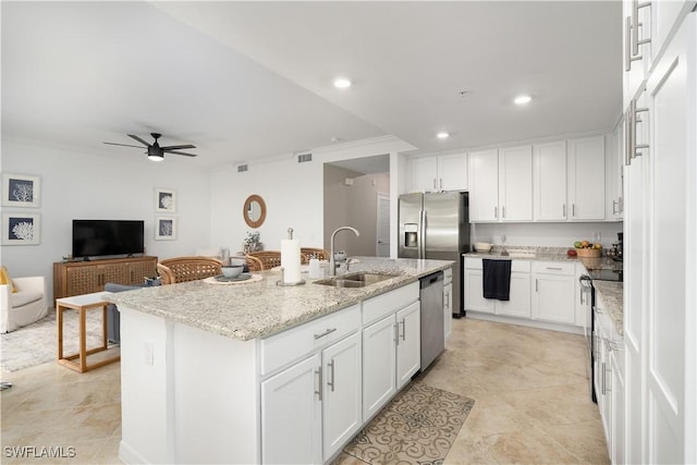 kitchen featuring white cabinetry, a center island with sink, appliances with stainless steel finishes, light stone countertops, and sink