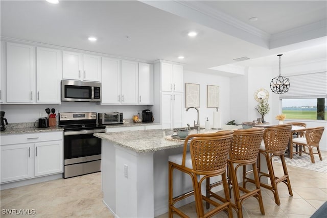 kitchen with appliances with stainless steel finishes, white cabinetry, and an island with sink