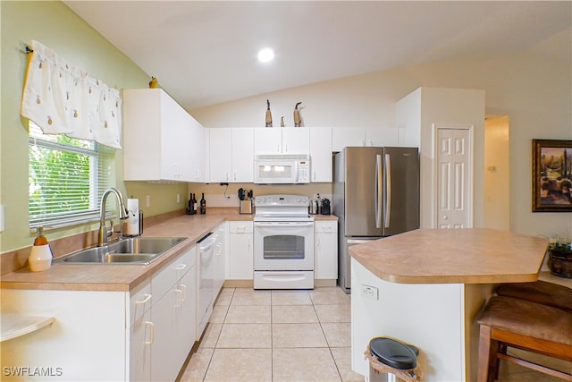 kitchen featuring vaulted ceiling, sink, white appliances, white cabinetry, and light tile patterned floors