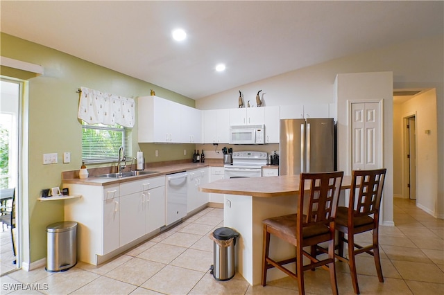 kitchen with white appliances, white cabinets, a center island, lofted ceiling, and sink