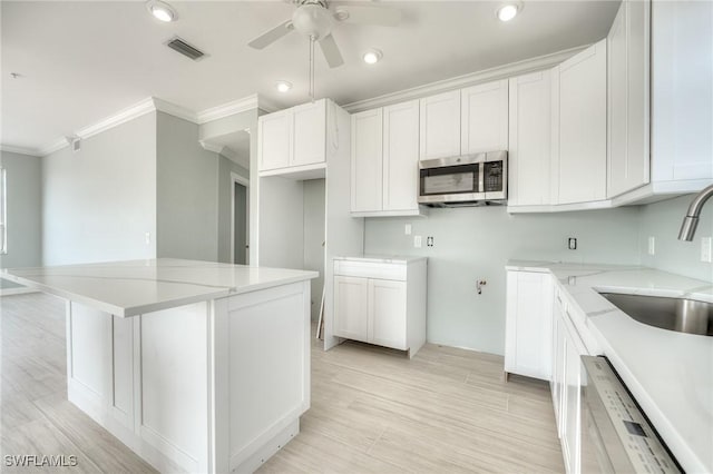 kitchen with white cabinetry, sink, light stone counters, and ornamental molding