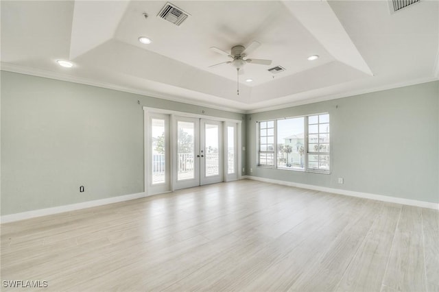 empty room featuring french doors, ceiling fan, a raised ceiling, crown molding, and light hardwood / wood-style flooring