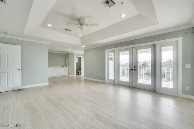 unfurnished living room featuring a raised ceiling, light hardwood / wood-style flooring, and french doors