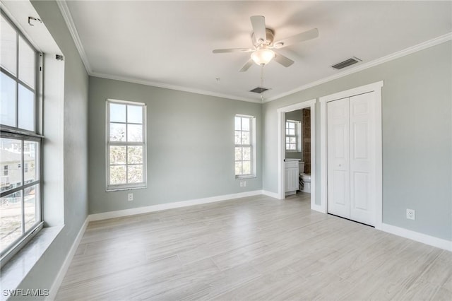 unfurnished bedroom featuring multiple windows, light hardwood / wood-style flooring, ornamental molding, and a closet