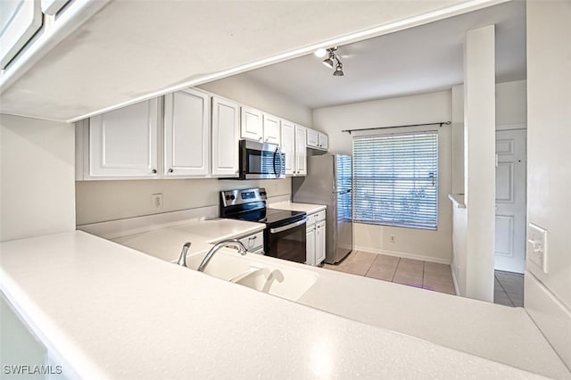 kitchen featuring light tile patterned floors, stainless steel appliances, light countertops, white cabinets, and a sink