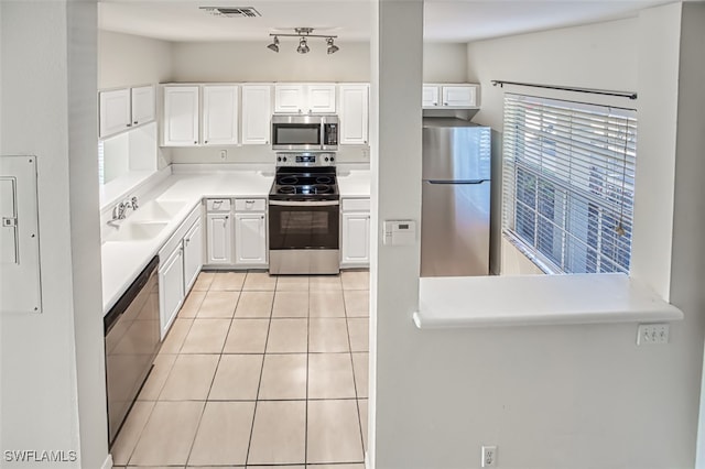 kitchen featuring light tile patterned floors, stainless steel appliances, visible vents, white cabinets, and a sink