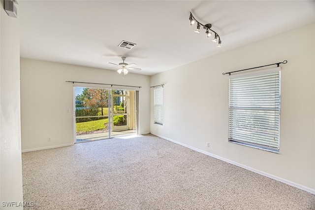 carpeted empty room featuring baseboards, visible vents, and a ceiling fan