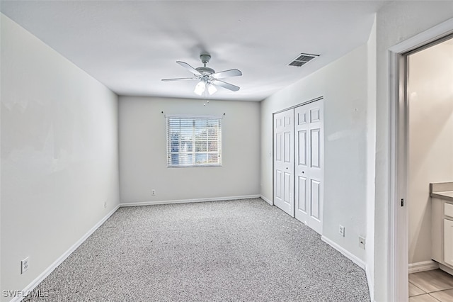 unfurnished bedroom with a closet, visible vents, light carpet, and baseboards