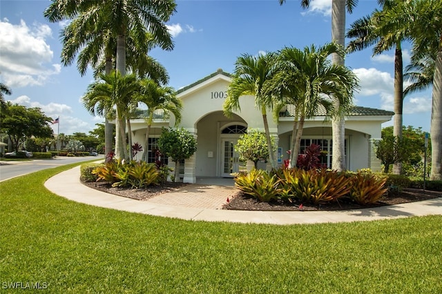 mediterranean / spanish house featuring a front lawn, french doors, and stucco siding