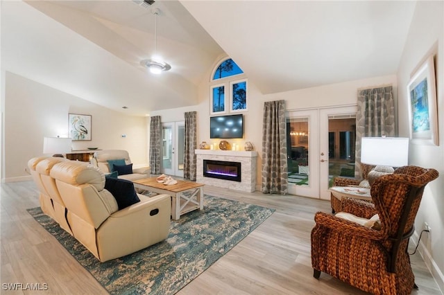 living room with lofted ceiling, light hardwood / wood-style floors, and french doors